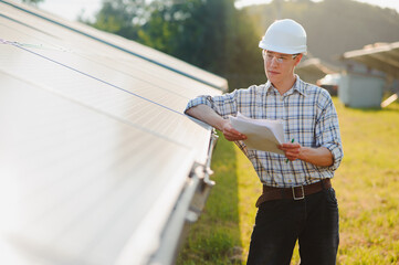 The portrait of a young engineer checks photovoltaic solar panels. Concept: renewable energy, technology, electricity, service, green power.