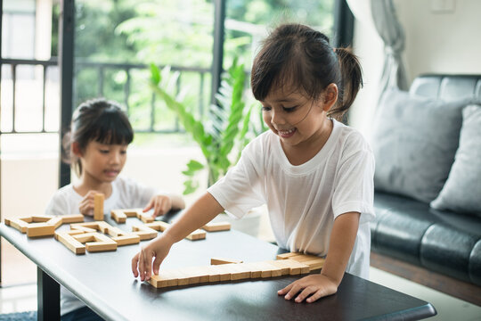 Two happy siblings playing a game with wooden blocks at home joyfully