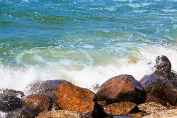 Fototapeta na wymiar sea waves break on the rocks, a lot of spray. Sunny day.
