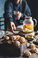 A woman reaches for a cake and drinks grapefruit tea. Healthy drink.