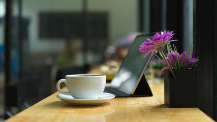Workspace with coffee cup, decoration and digital tablet on counter bar in coffee shop