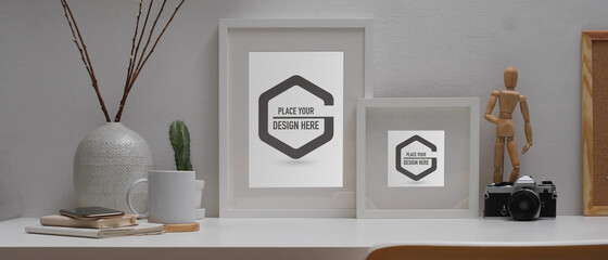 Home office desk with mock up frames, camera, stationery and decorations