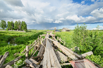 Fototapeta na wymiar Ruined wooden bridge in the Russian village