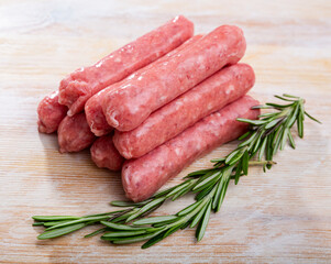 Raw farm sausages with rosemary on wooden table. High quality photo