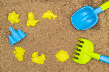 Fototapeta na wymiar Colored shovel and rake and molds in sandbox. Outdoor children's sand toys. Summer concept. With place for text.