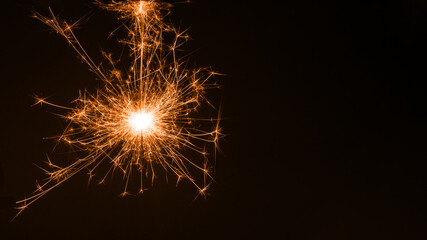 Burning colored sparkler, pyrotechnics on a black background. Merry christmas and happy new year, background, copy space