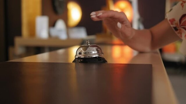 Close-up of a girl pressing the bell at the hotel reception. Slow motion. Hand of a woman using a hotel bell.