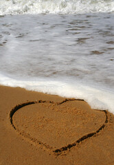 A love heart in the sand with the ocean waves rolling in