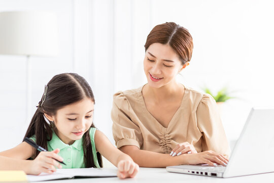 Mother Is Working And Teaching Her Daughter Doing Home Work