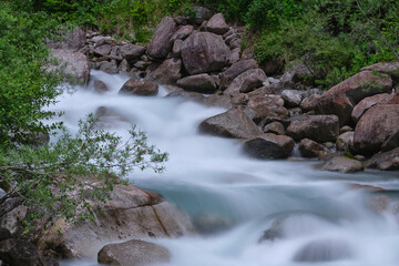 Waterfall in mountain river with rocks. Rapid stream with bright blurred blue waves. long exposure.  Big boulders in clear water of mountain river.