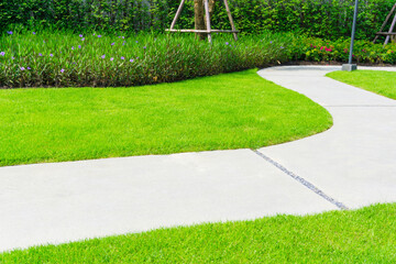 Gray walkway on green grass lawn in garden, sand washed finishing pavement