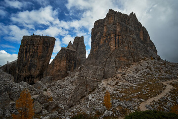 Rugged and rocky alpine mountain ranges with cloudy blue sky above in The Dolomites. These iconic mountain peaks are located at Cinque Torri in the Tyrol region of Italy.