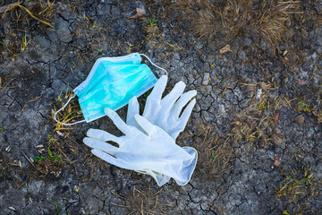 Medical face mask and gloves laying on the ground at the street. 
