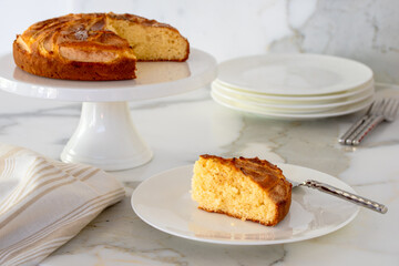 Cake slice on plate with cake on cake stand for afternoon tea