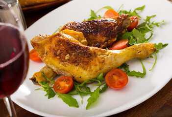 Plate of tasty snack - roasted chicken legs with arugula and cherry tomatoes