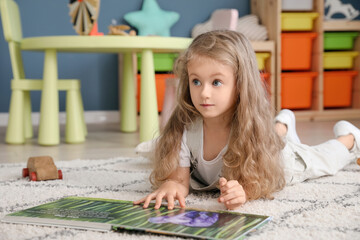 Cute little girl reading book at home