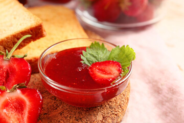 Bowl of tasty strawberry jam on table, closeup