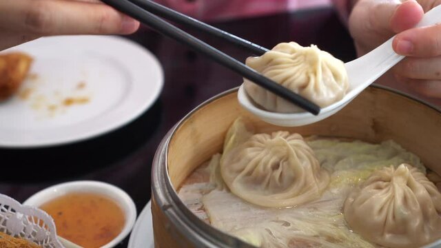 Hand chopsticks eating xiaolongbao soup dumpling in Chinese restaurant