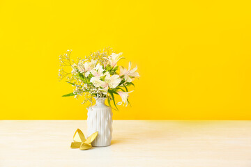 Beautiful vase with flowers on table against color background