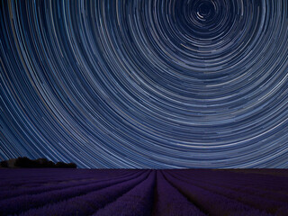 Digital composite image of star trails around Polaris with Vibrant landscape of beautiful lavender field