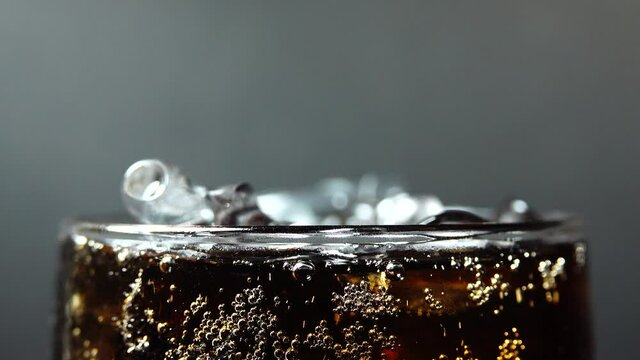 4K Filling up a cup with Coca close up. macro shot of bubbles in soda, red epic, drops of water flowing down the glass, sizzling foam drink ice glass