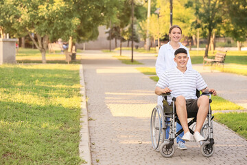 Doctor and young man in wheelchair outdoors