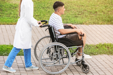 Obraz premium Doctor and young man in wheelchair outdoors