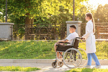 Doctor and young man in wheelchair outdoors