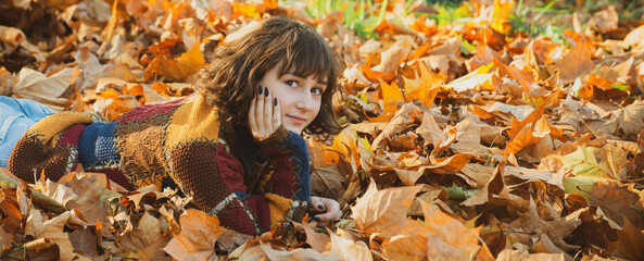 Close up portrait of smiling young pretty girl in the fall time. Autumn girl in city park. Dreamy beautiful girl with long natural black hair on autumn background with colorful leaves.