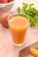 Glass of tasty peach juice on color background