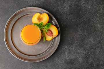 Glass of tasty peach juice on dark background