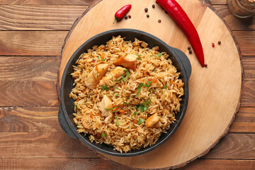 Frying pan with tasty pilaf on table