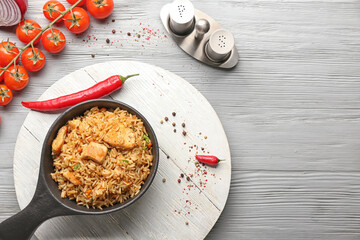 Frying pan with tasty pilaf on table