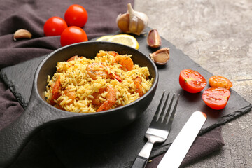 Frying pan with tasty pilaf on grey background