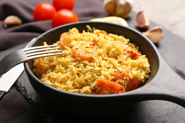 Frying pan with tasty pilaf on table
