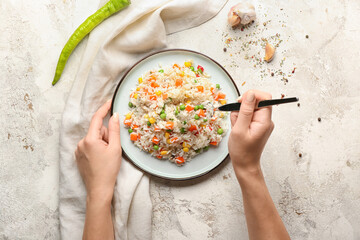 Woman eating tasty pilaf on table
