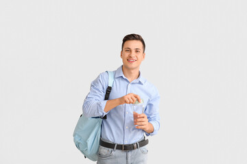 Young man with bottle of water on light background