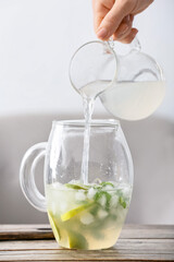Woman making tasty mojito cocktail at table