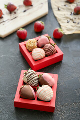 Boxes with tasty glazed strawberry on dark background
