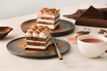 Plates with tasty tiramisu and tea on table