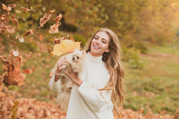 Obraz premium Autumn beauty. Woman with doggy on fall maple leaf outdoors. Happiness carefree with pets. Emotional support.