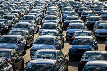 Rows of a new cars parked in a distribution center on a car factory on a sunny day. Top view to the parking in the open air. © Eugene_Photo