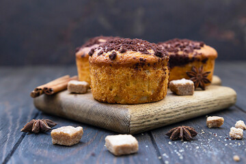 Tasty spicy muffins with chocolate streusel and cinnamon and anise star on wooden cutting board, rustic background.