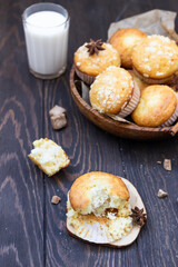 Vanilla cinnamon crumble muffins with coconut filling, spices and glass of milk on wooden table. Rustic background.