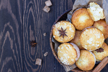 Vanilla cinnamon crumble muffins with coconut filling, spices and glass of milk on wooden table. Rustic background.