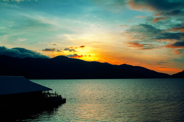 Silhouette of mountain , landscape sunrise on sky  and lake view with shadow of  floating raft house on background