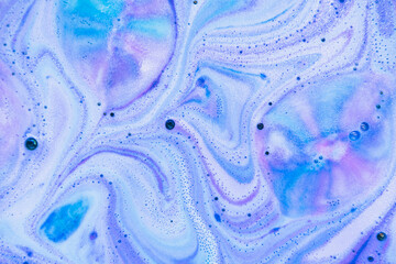 Beautiful bath bomb dissolves in blue, purple and pink colors in the water. Flat lay, top view, directly above. Abstract background - 370487555