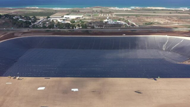 Water reservoir construction site with newly installed plastic lining sheets, Aerial view.