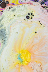 Bath foam with yellow and purple rainbow colors with bubbles in the water. Galaxy imagination. Marble texture background effect. Flat lay, top view, directly above