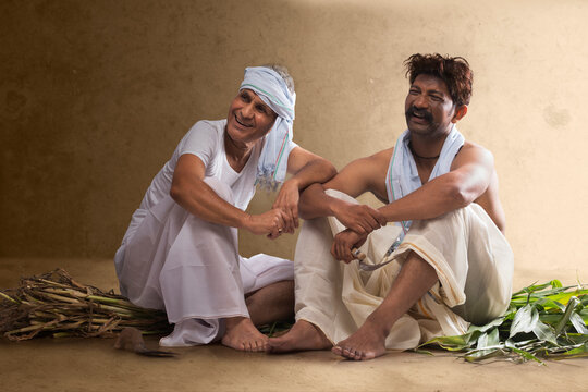 Two smiling  Indian farmer sitting together	